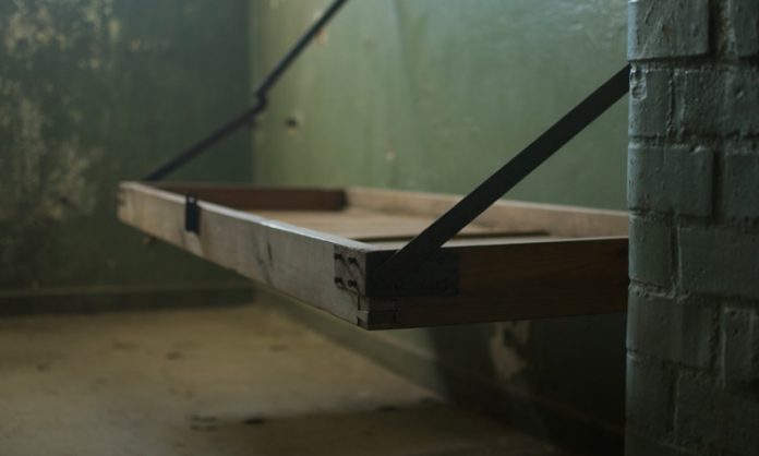 Ein aufgeklapptes Pritschenbett in einer Gefängniszelle