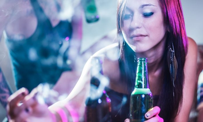 Eine Jugendliche trinkt Bier und raucht Cannabis