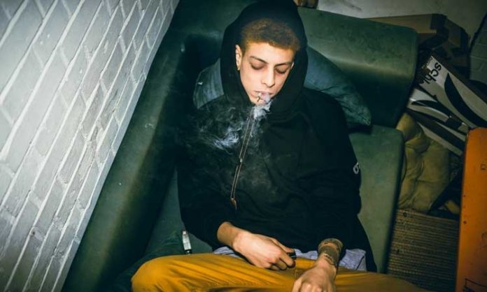 Ein Jugendlicher raucht einen Joint auf Couch