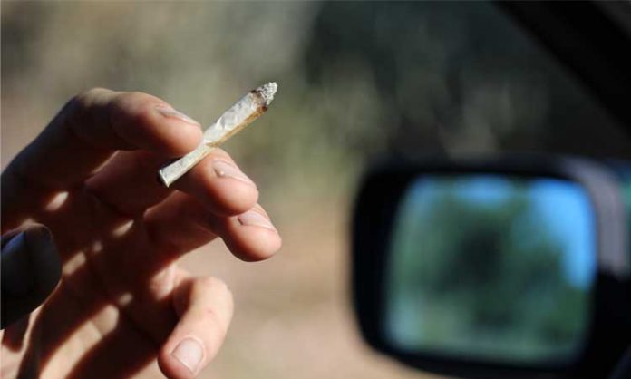 Ein Mann raucht einen Cannabis-Joint im Auto